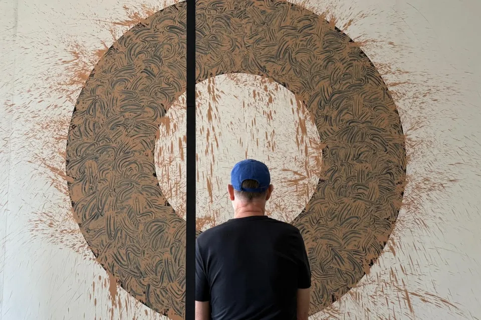 Photo of man looking at large painting.